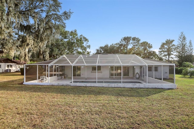 rear view of property with a yard, glass enclosure, and a patio area