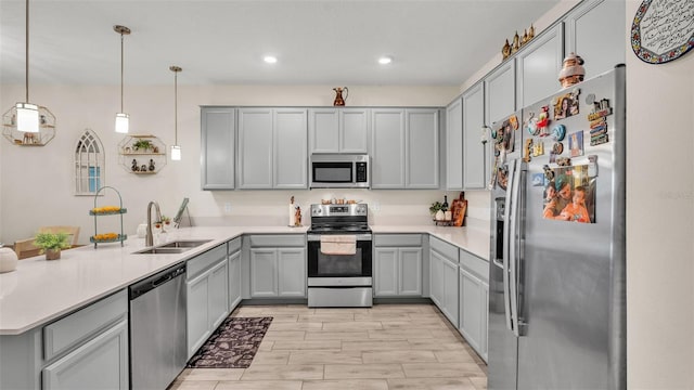 kitchen featuring gray cabinetry, sink, kitchen peninsula, decorative light fixtures, and appliances with stainless steel finishes