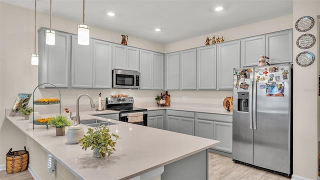 kitchen with pendant lighting, sink, gray cabinets, kitchen peninsula, and stainless steel appliances