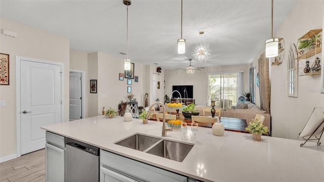 kitchen featuring stainless steel dishwasher, pendant lighting, sink, and light hardwood / wood-style flooring