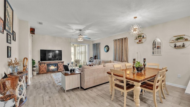 interior space featuring ceiling fan with notable chandelier, light wood-type flooring, and a textured ceiling