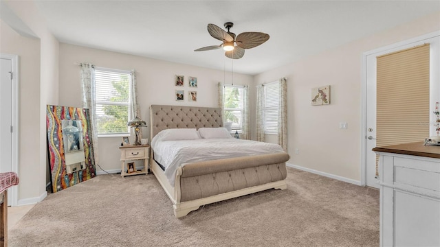 bedroom with ceiling fan, light carpet, and multiple windows