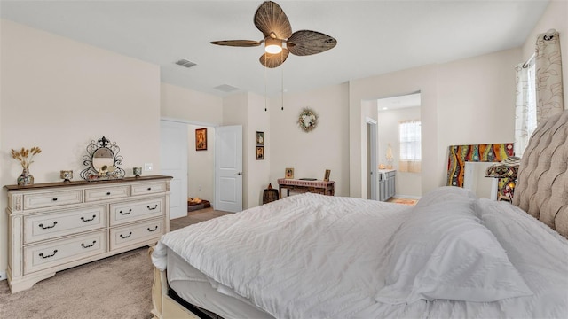 bedroom featuring light colored carpet, ensuite bath, and ceiling fan