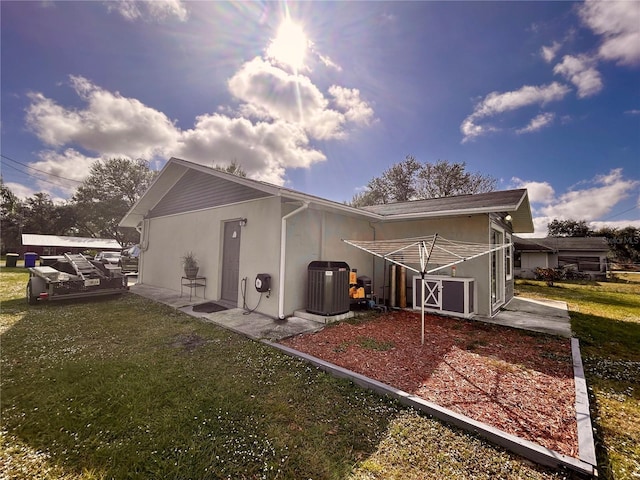 back of property featuring a lawn, central air condition unit, and a patio