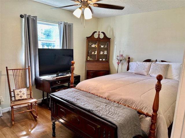 bedroom with hardwood / wood-style flooring, ceiling fan, and a textured ceiling