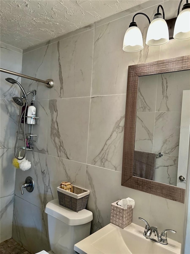 bathroom with a tile shower, a textured ceiling, sink, tile walls, and toilet