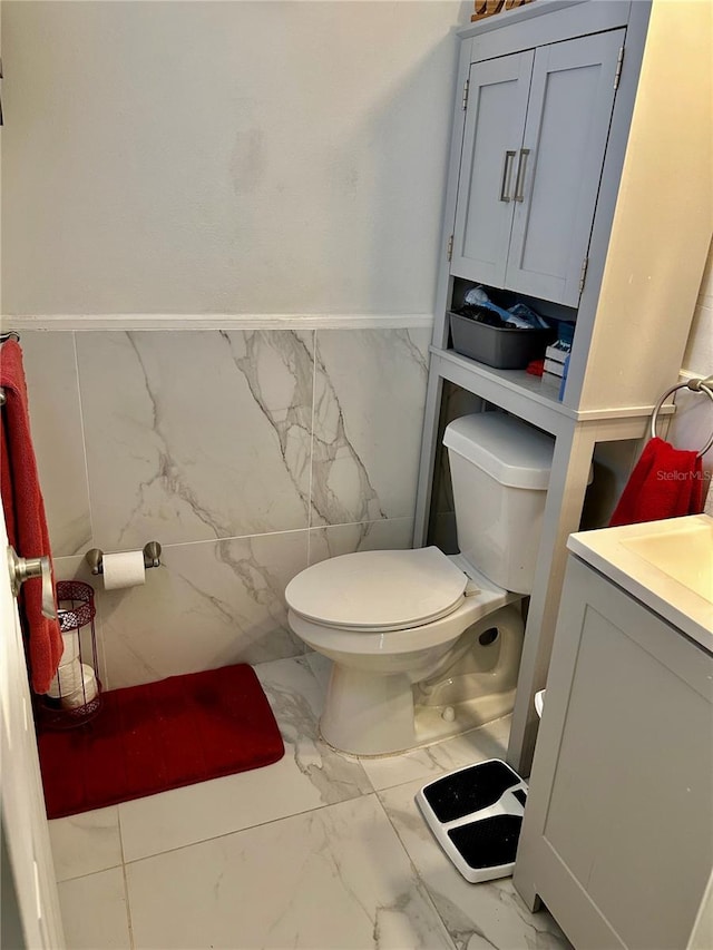 bathroom featuring vanity, toilet, and tile walls