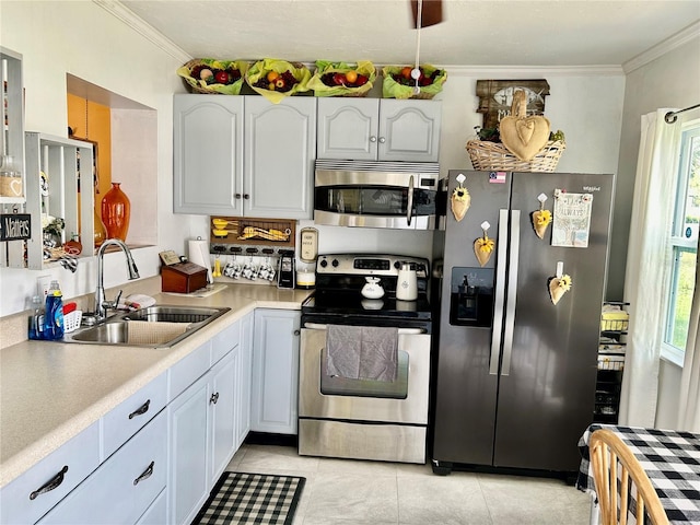 kitchen with sink, stainless steel appliances, light tile patterned floors, white cabinets, and ornamental molding