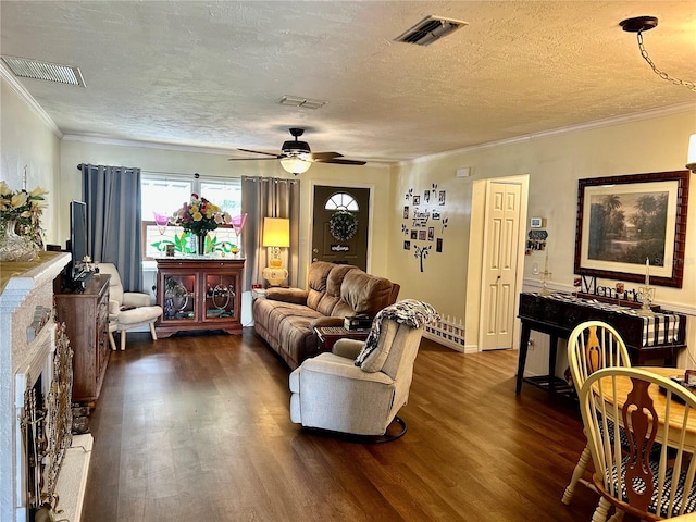 living room featuring ceiling fan, dark hardwood / wood-style flooring, crown molding, a textured ceiling, and a fireplace