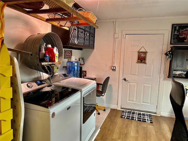 washroom with wood-type flooring, crown molding, and washing machine and clothes dryer