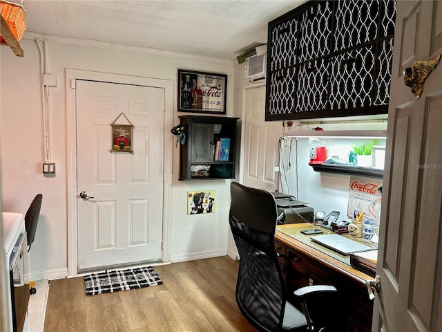 home office featuring a wall unit AC, crown molding, light hardwood / wood-style flooring, and a textured ceiling