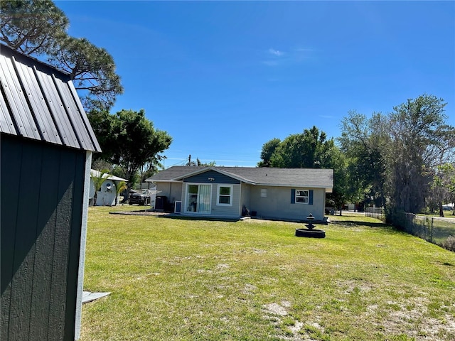 back of property with a lawn and fence