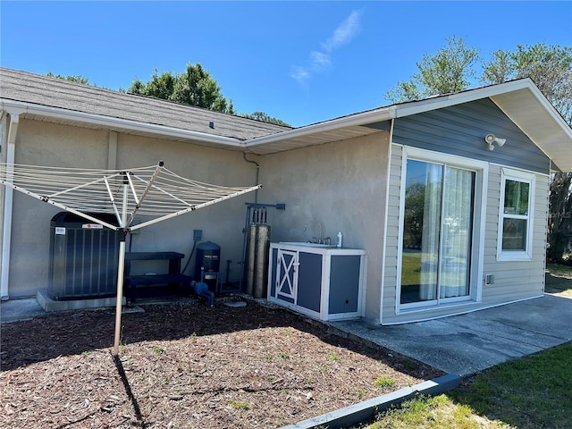 view of side of property featuring stucco siding, central air condition unit, and a patio area