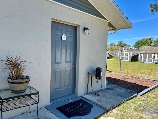 view of exterior entry featuring stucco siding and a yard