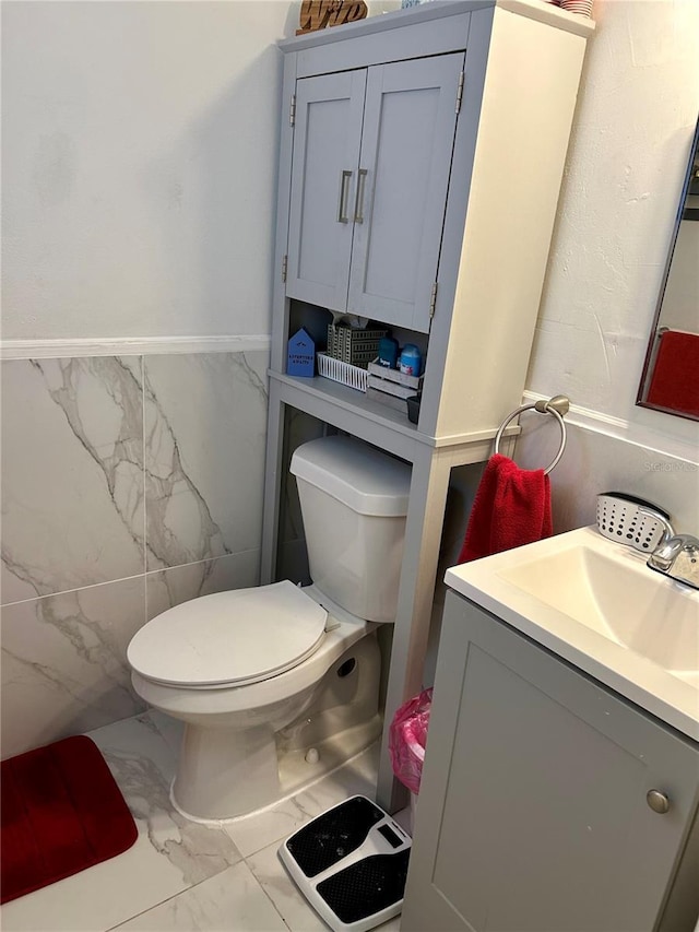 half bath featuring marble finish floor, toilet, and vanity