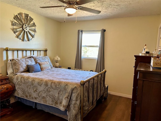 bedroom featuring baseboards, a ceiling fan, dark wood-type flooring, and a textured ceiling