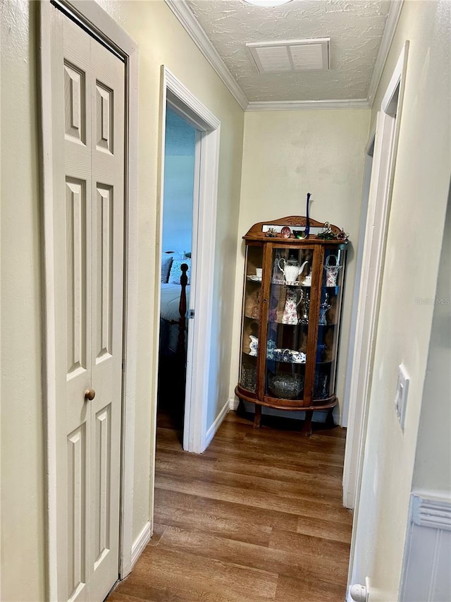 corridor with visible vents, crown molding, wood finished floors, and a textured ceiling