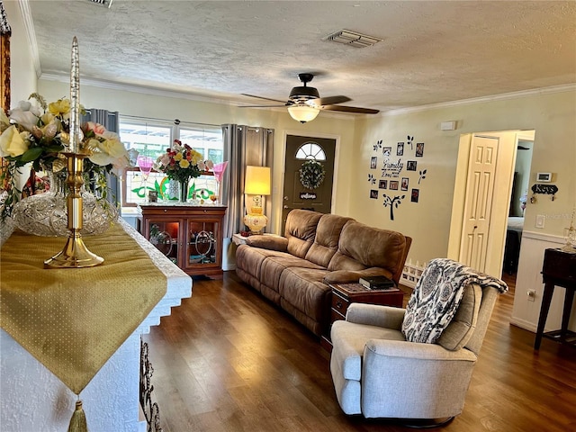 living area featuring ornamental molding, dark wood-style floors, a textured ceiling, and visible vents