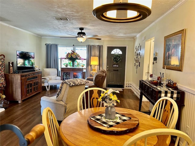 dining area featuring a ceiling fan, wood finished floors, a textured ceiling, visible vents, and ornamental molding
