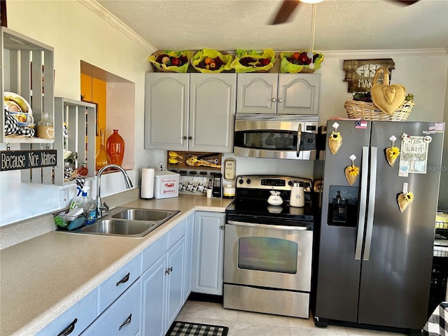 kitchen with light countertops, a sink, appliances with stainless steel finishes, ceiling fan, and ornamental molding