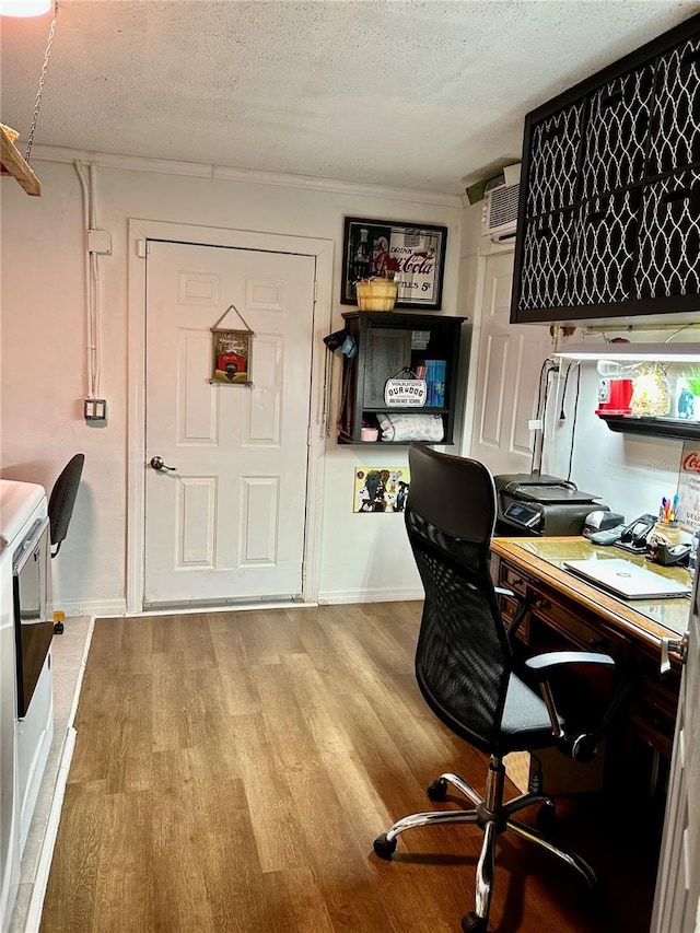 office with baseboards, a textured ceiling, a wall mounted air conditioner, and wood finished floors