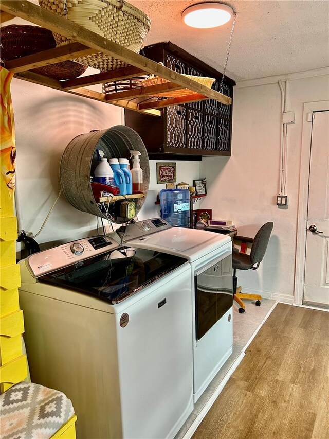 clothes washing area with separate washer and dryer, wood finished floors, laundry area, and a textured ceiling