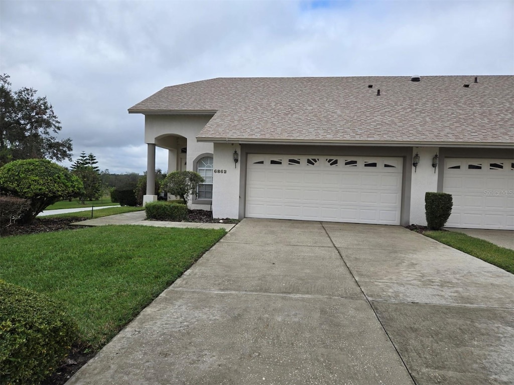 ranch-style home with a garage and a front lawn