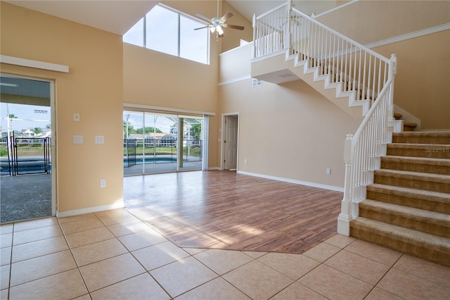 interior space featuring a towering ceiling, ceiling fan, and light tile patterned flooring