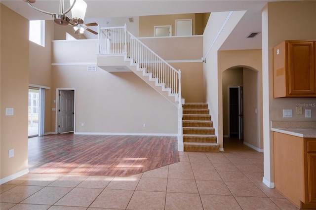 interior space featuring a wealth of natural light, tile patterned flooring, ceiling fan, and a high ceiling