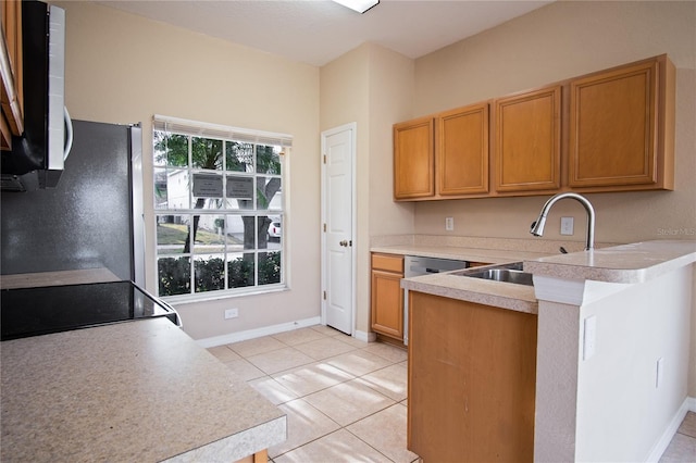 kitchen with range, sink, stainless steel fridge, light tile patterned flooring, and kitchen peninsula