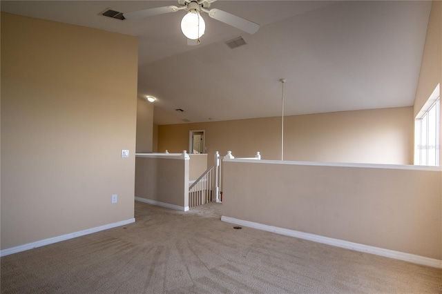 spare room featuring ceiling fan, light colored carpet, and lofted ceiling