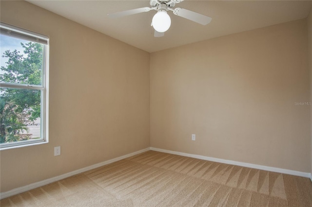 carpeted empty room with ceiling fan and plenty of natural light