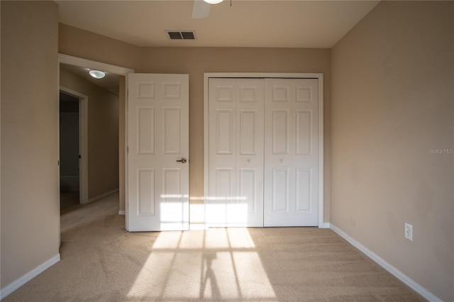 unfurnished bedroom featuring ceiling fan, light carpet, and a closet