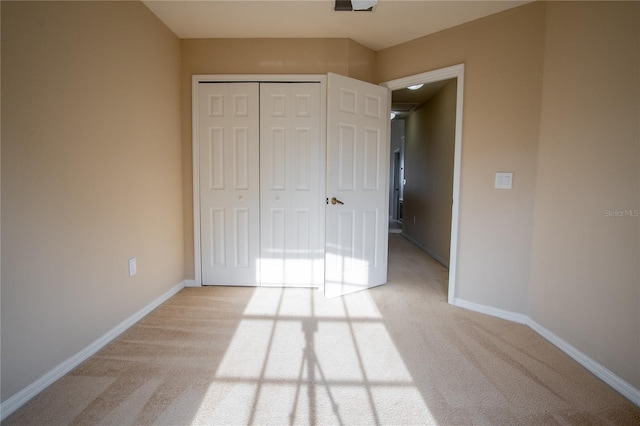 unfurnished bedroom with light carpet and a closet