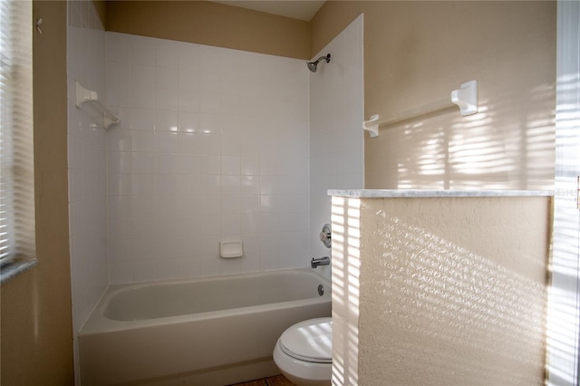 bathroom featuring tiled shower / bath combo and toilet