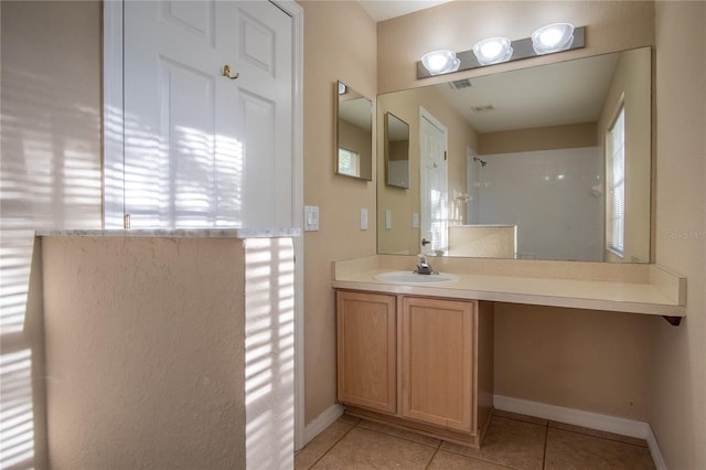 bathroom featuring tile patterned flooring, vanity, and tiled shower