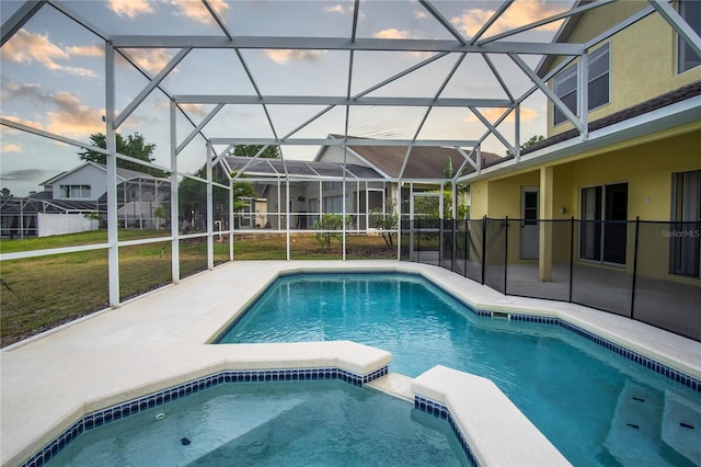 pool at dusk featuring a lanai, a yard, and a patio