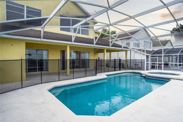 view of swimming pool with a patio area, an in ground hot tub, and glass enclosure