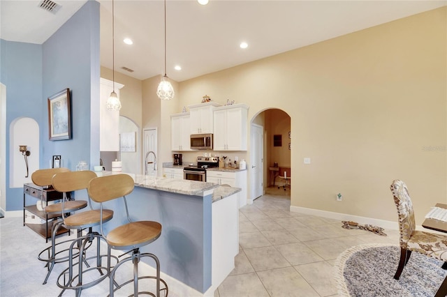 kitchen featuring pendant lighting, white cabinetry, light stone counters, kitchen peninsula, and stainless steel appliances