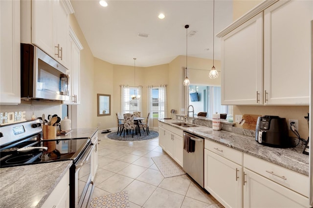 kitchen with light stone countertops, sink, stainless steel appliances, decorative light fixtures, and light tile patterned floors