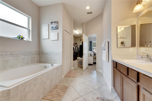 bathroom with tile patterned flooring, vanity, and tiled bath