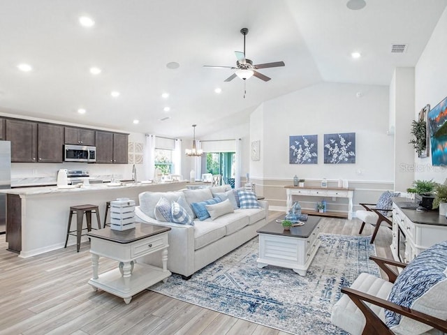 living room featuring ceiling fan with notable chandelier, lofted ceiling, sink, and light hardwood / wood-style flooring