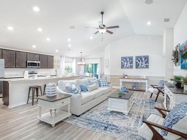 living room featuring ceiling fan with notable chandelier, light hardwood / wood-style floors, lofted ceiling, and sink