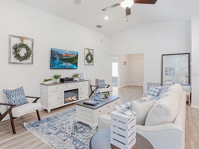 living room with ceiling fan, vaulted ceiling, and light hardwood / wood-style flooring