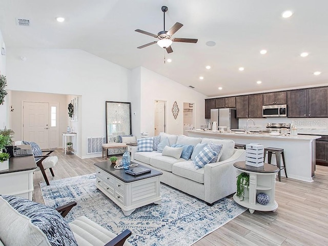 living room with ceiling fan, light hardwood / wood-style floors, and lofted ceiling