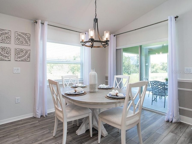 dining area with hardwood / wood-style floors, vaulted ceiling, and a chandelier