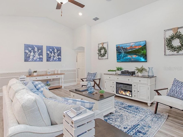 living room with ceiling fan, light hardwood / wood-style floors, and lofted ceiling