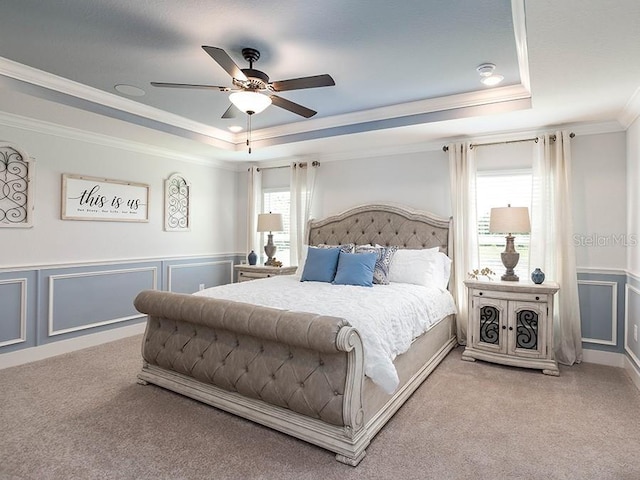 bedroom with a tray ceiling, ceiling fan, crown molding, and carpet floors