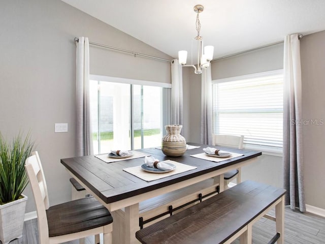 dining area featuring a chandelier, vaulted ceiling, and light wood-type flooring