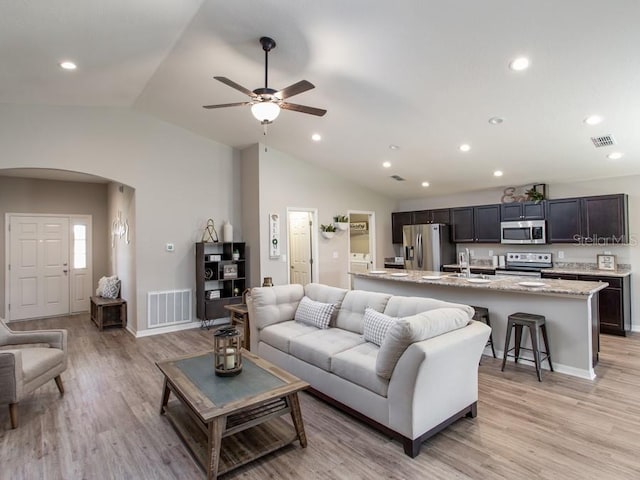 living room featuring ceiling fan, lofted ceiling, sink, and light hardwood / wood-style flooring